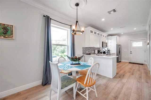 dining space featuring light wood-type flooring, crown molding, and a chandelier