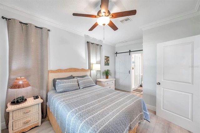 bedroom with light hardwood / wood-style flooring, ceiling fan, ornamental molding, and a barn door