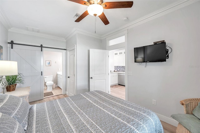 bedroom with a barn door, connected bathroom, ornamental molding, and light hardwood / wood-style flooring