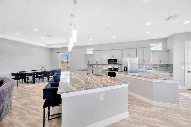 kitchen with a large island, sink, decorative light fixtures, and appliances with stainless steel finishes