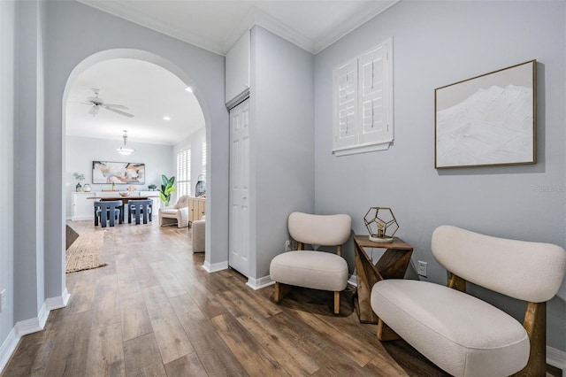 living area with crown molding, ceiling fan, and dark hardwood / wood-style floors