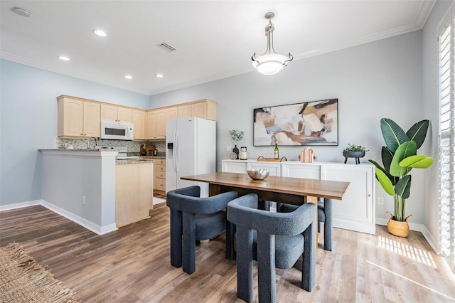 dining area featuring light wood-type flooring and crown molding