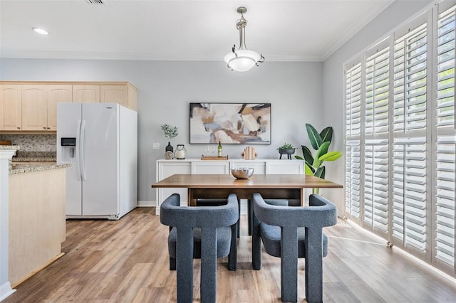 dining space with ornamental molding and light hardwood / wood-style floors