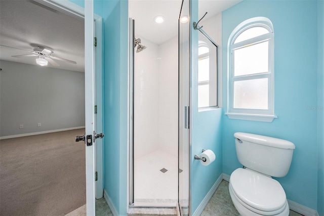 bathroom with ceiling fan, toilet, and a shower with shower door