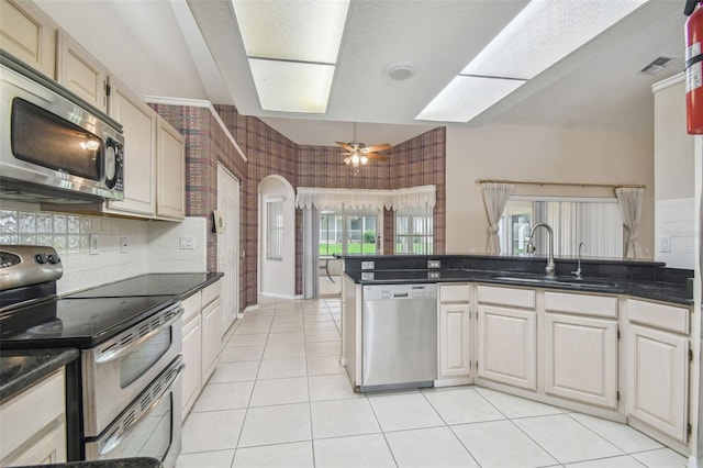 kitchen featuring light tile patterned floors, stainless steel appliances, kitchen peninsula, sink, and ceiling fan