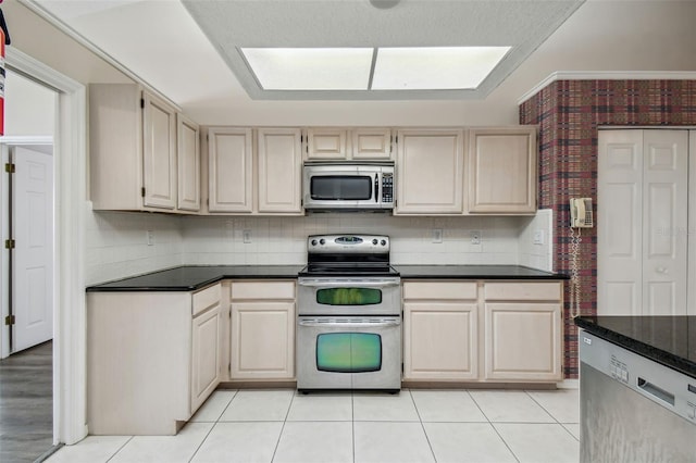 kitchen with light tile patterned floors, appliances with stainless steel finishes, and dark stone counters