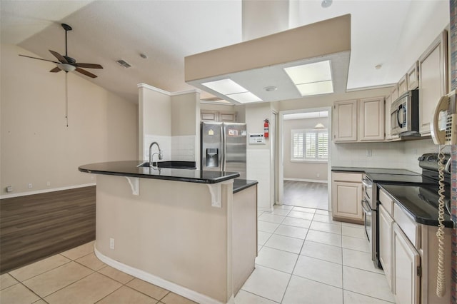 kitchen featuring a kitchen bar, ceiling fan, light wood-type flooring, and appliances with stainless steel finishes