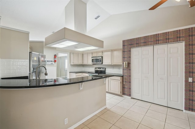 kitchen with light tile patterned floors, vaulted ceiling, cream cabinets, ceiling fan, and appliances with stainless steel finishes