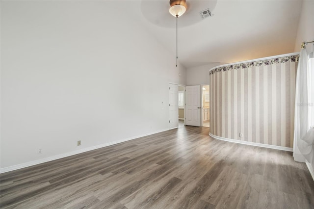 unfurnished room with lofted ceiling, a healthy amount of sunlight, ceiling fan, and dark hardwood / wood-style floors