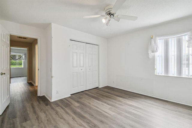 unfurnished bedroom featuring ceiling fan, a closet, and dark hardwood / wood-style flooring