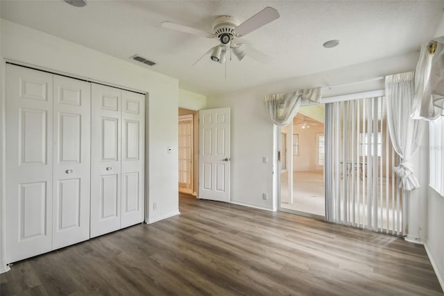 unfurnished bedroom with a textured ceiling, dark hardwood / wood-style flooring, ceiling fan, and a closet