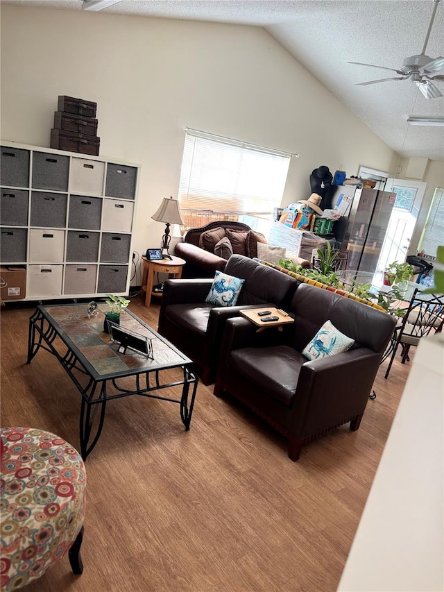 living room featuring lofted ceiling, ceiling fan, a textured ceiling, and light hardwood / wood-style floors