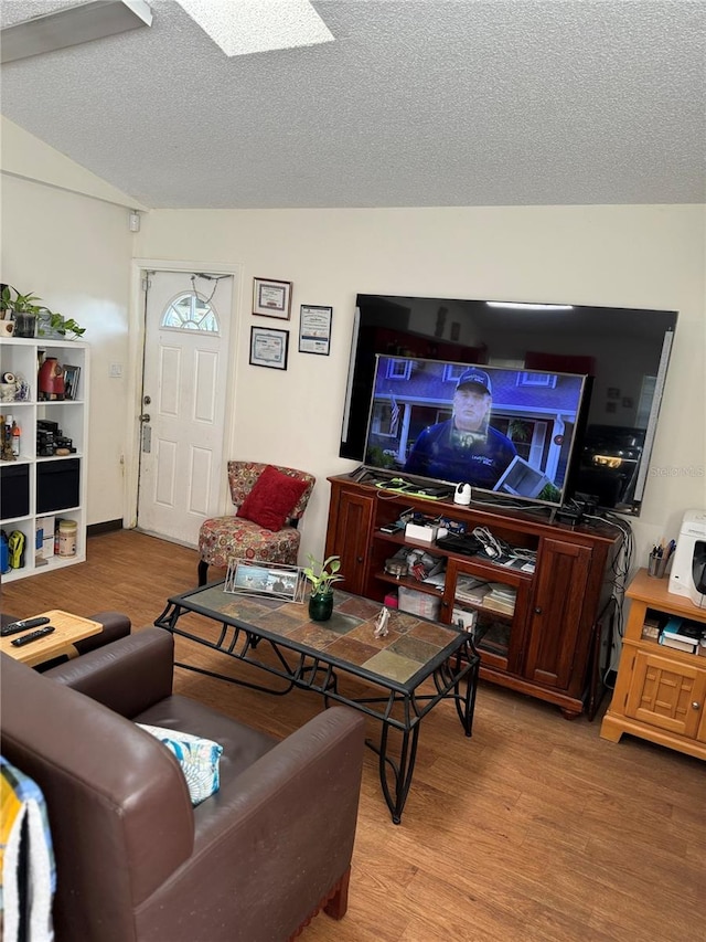 living room featuring a textured ceiling, hardwood / wood-style flooring, and lofted ceiling with skylight