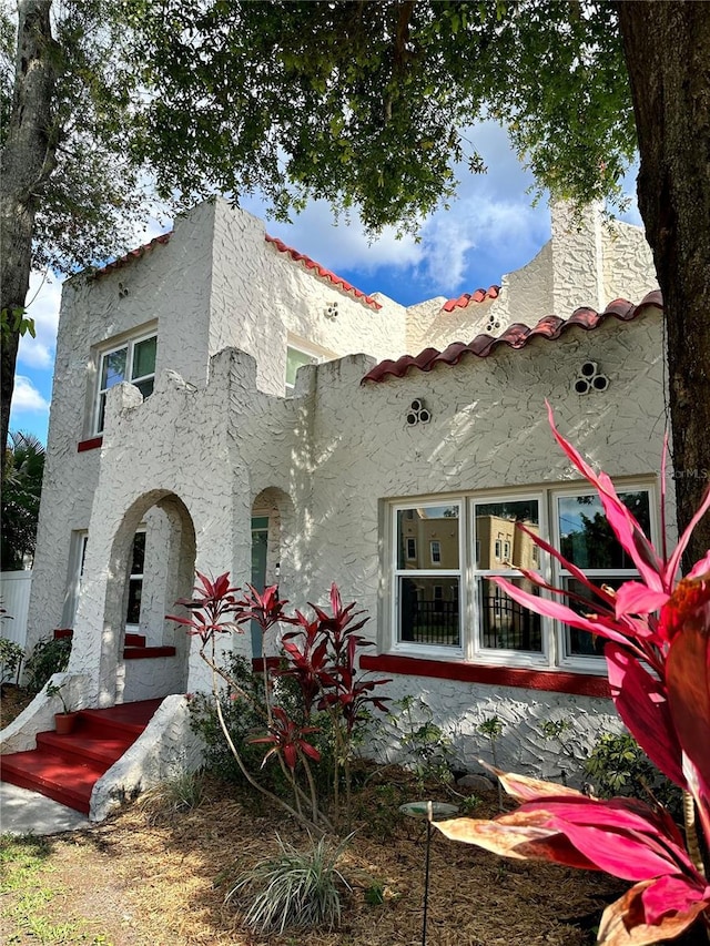 back of property featuring stucco siding, a tiled roof, and a chimney