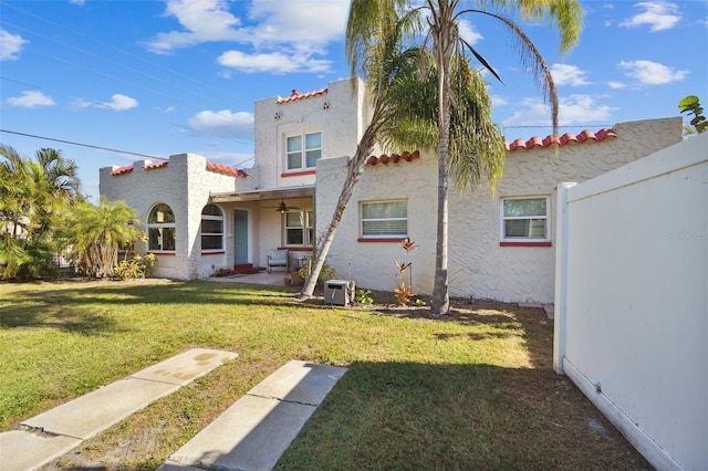 view of front facade with ceiling fan and a front lawn