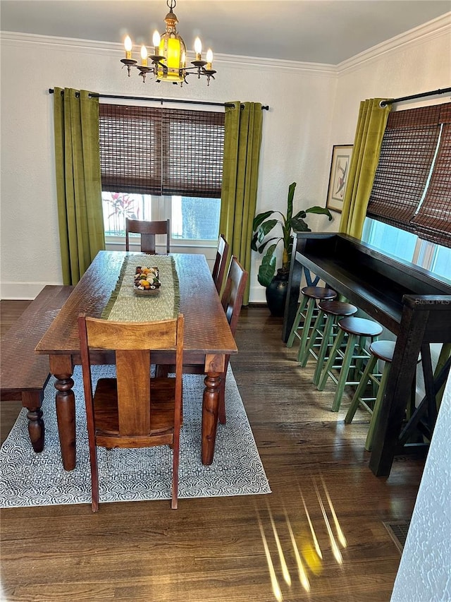 dining area featuring dark wood-type flooring, ornamental molding, and an inviting chandelier