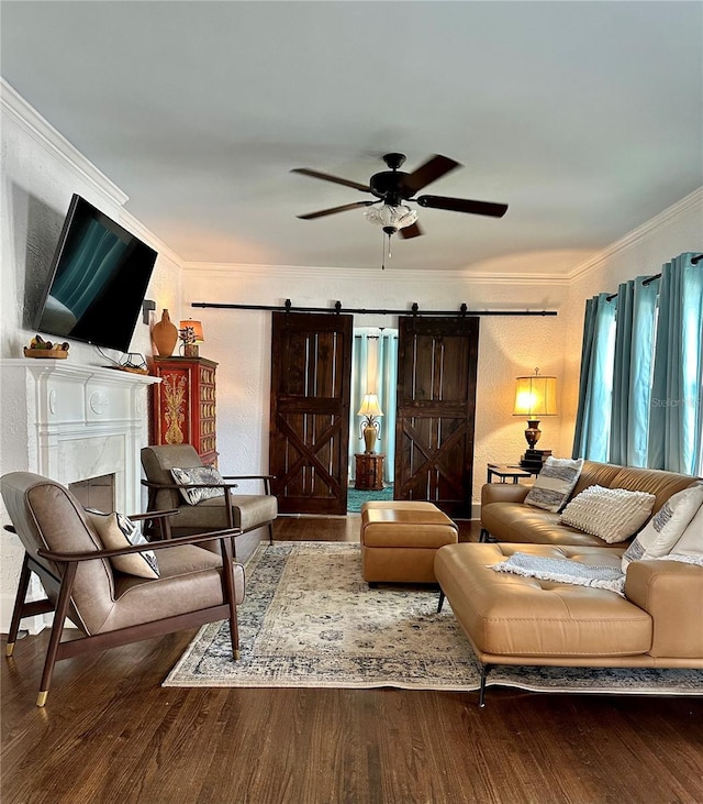 living room featuring hardwood / wood-style flooring, ceiling fan, a barn door, and crown molding