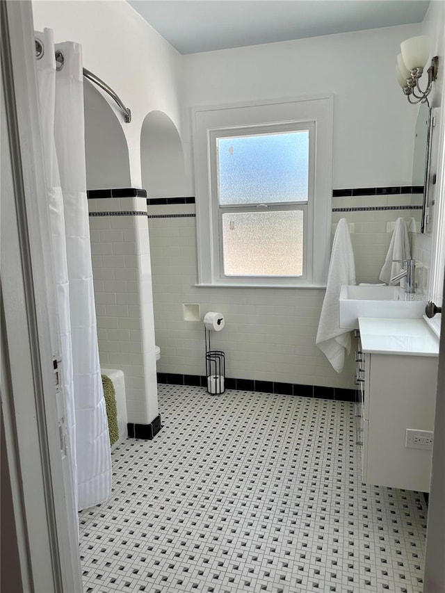 full bathroom with toilet, vanity, shower / tub combo with curtain, and tile walls