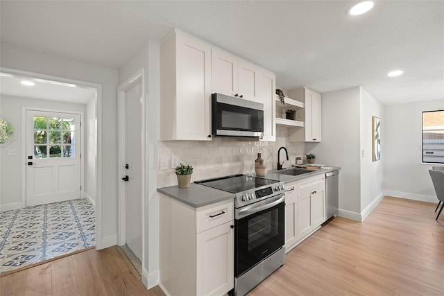 kitchen featuring appliances with stainless steel finishes, light wood-type flooring, sink, and white cabinets