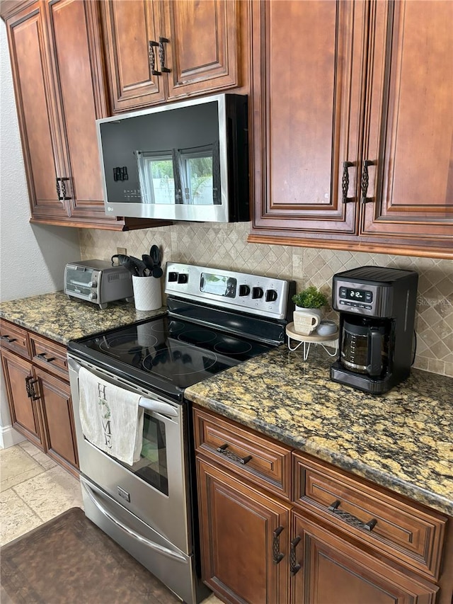 kitchen with tasteful backsplash, dark stone counters, and appliances with stainless steel finishes