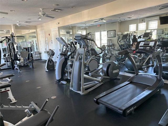 exercise room with ceiling fan and a textured ceiling