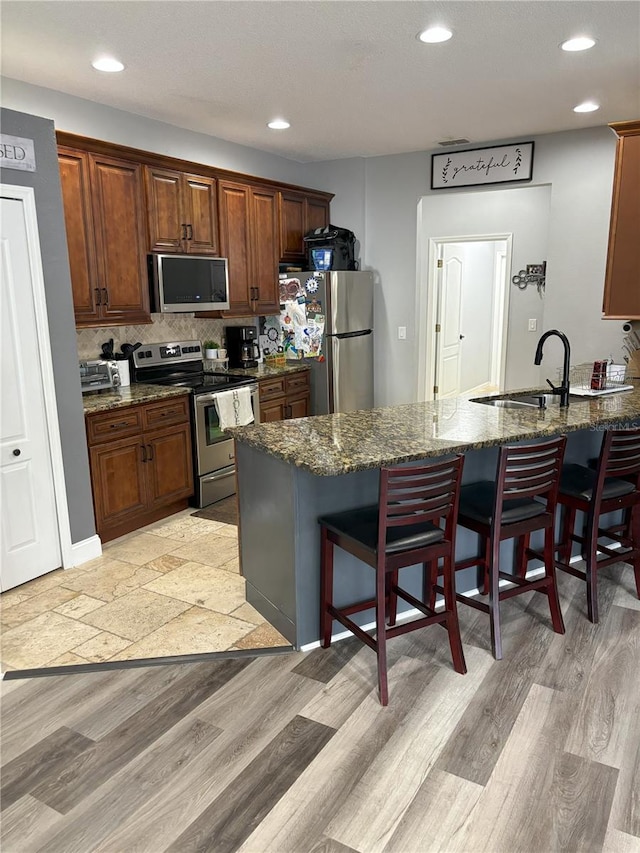 kitchen featuring dark stone countertops, sink, a breakfast bar area, and stainless steel appliances