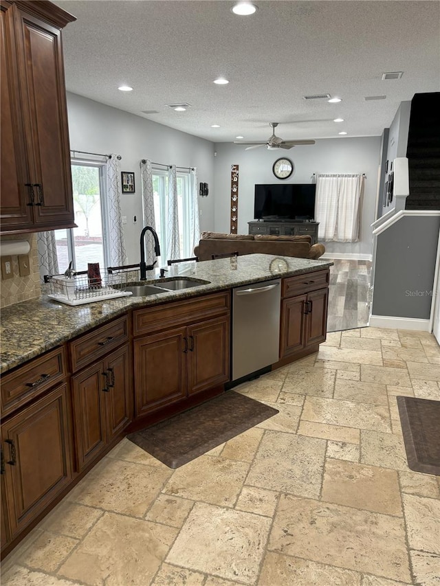 kitchen with dishwasher, sink, dark stone counters, ceiling fan, and a textured ceiling