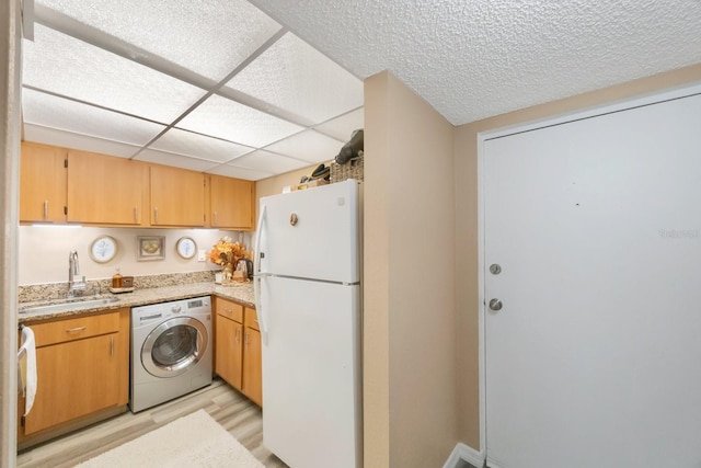 kitchen with white fridge, washer / dryer, sink, a paneled ceiling, and light wood-type flooring