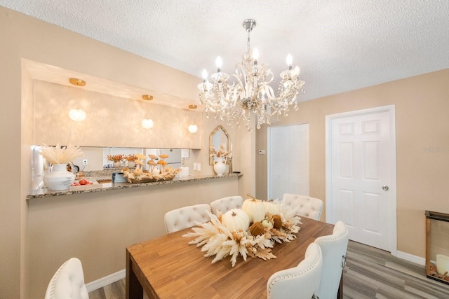 dining room with a textured ceiling, an inviting chandelier, and dark hardwood / wood-style flooring