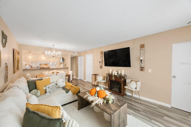 living room with a fireplace, hardwood / wood-style flooring, a textured ceiling, and a chandelier