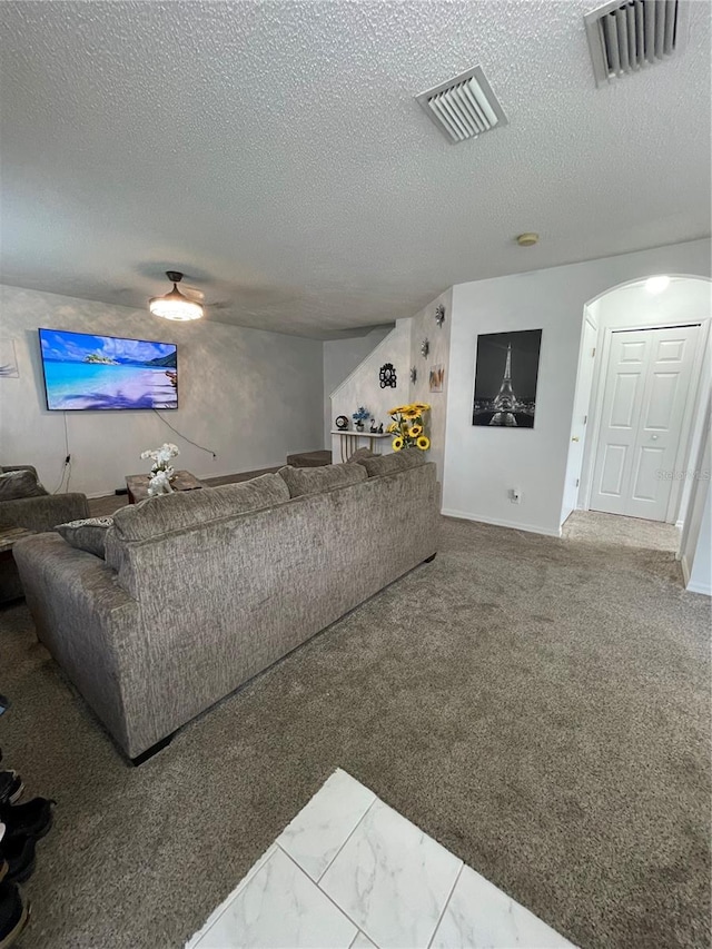 carpeted living room featuring a textured ceiling and ceiling fan