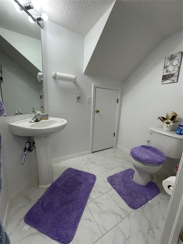 bathroom with a textured ceiling, lofted ceiling, and toilet