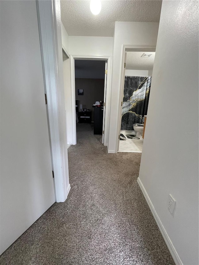 hallway featuring carpet floors and a textured ceiling