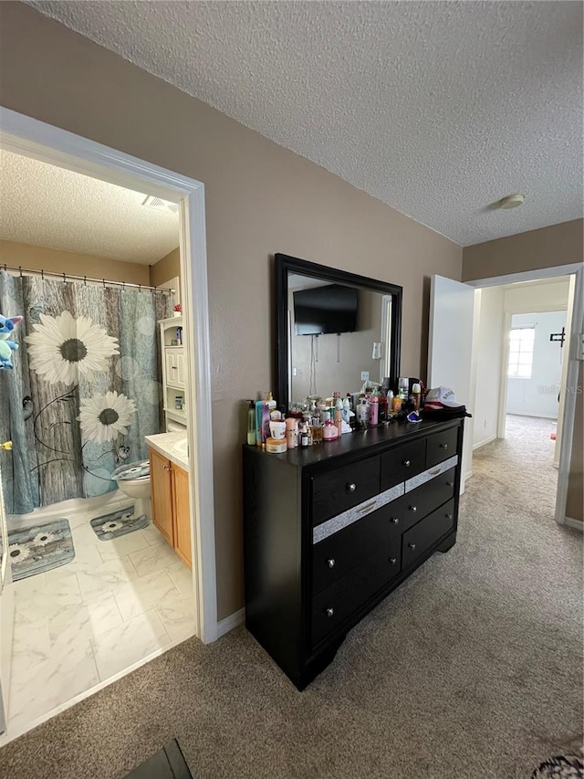 interior space with light carpet, a textured ceiling, and ensuite bathroom