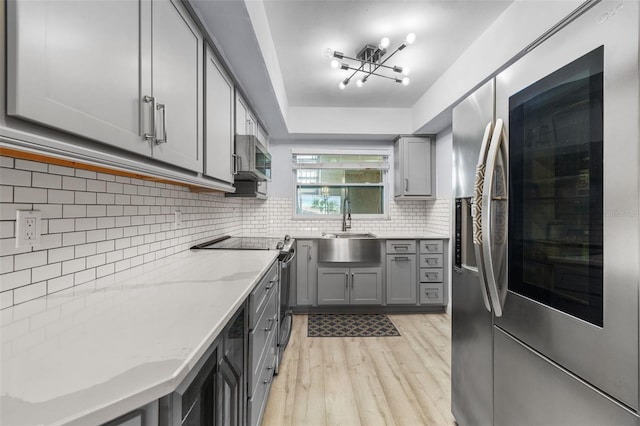 kitchen featuring light wood-type flooring, appliances with stainless steel finishes, gray cabinets, and sink