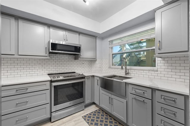 kitchen featuring appliances with stainless steel finishes, light hardwood / wood-style flooring, sink, and gray cabinetry