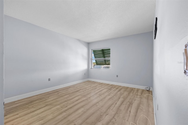 empty room with a textured ceiling and light hardwood / wood-style floors