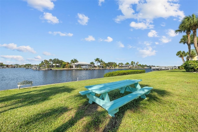 surrounding community with a water view and a yard