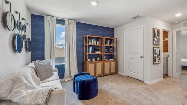 sitting room featuring a textured ceiling and light colored carpet