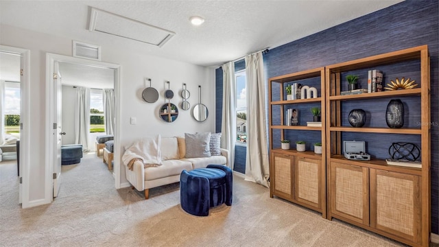 living room featuring carpet, baseboards, visible vents, attic access, and a textured ceiling