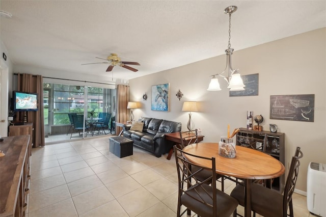 dining area featuring ceiling fan with notable chandelier, a textured ceiling, and light tile patterned floors