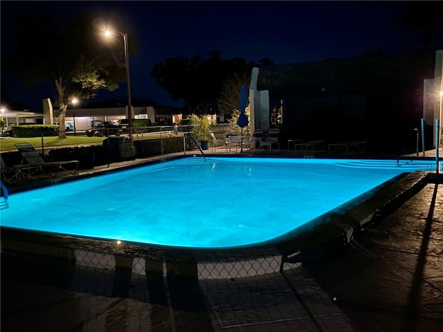 view of pool at twilight