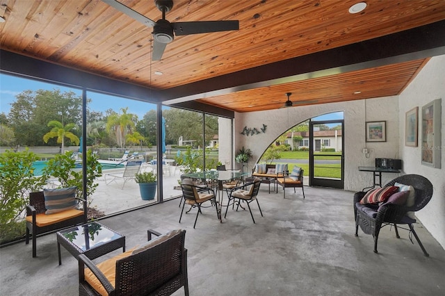 sunroom / solarium featuring ceiling fan, beamed ceiling, and wooden ceiling