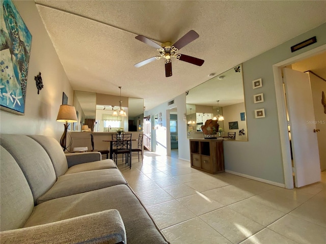 living room featuring ceiling fan with notable chandelier, tile patterned floors, and a textured ceiling