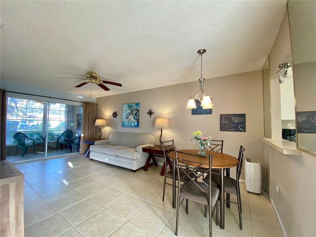 tiled dining space featuring ceiling fan with notable chandelier and a textured ceiling