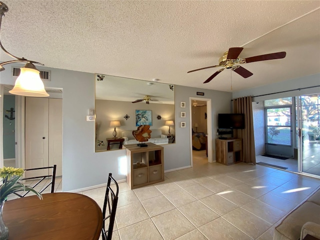 tiled dining area with ceiling fan and a textured ceiling