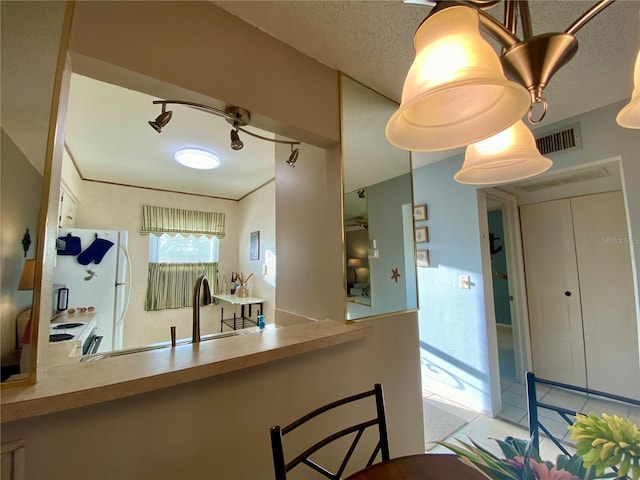 kitchen with white appliances, kitchen peninsula, sink, and a textured ceiling