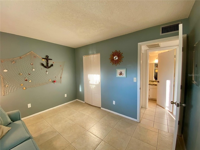 interior space with light tile patterned floors, a closet, and a textured ceiling