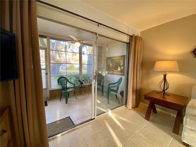 doorway with light tile patterned flooring, ceiling fan, and a textured ceiling