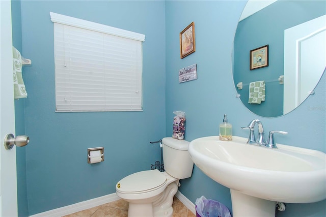 bathroom with toilet, sink, and tile patterned floors